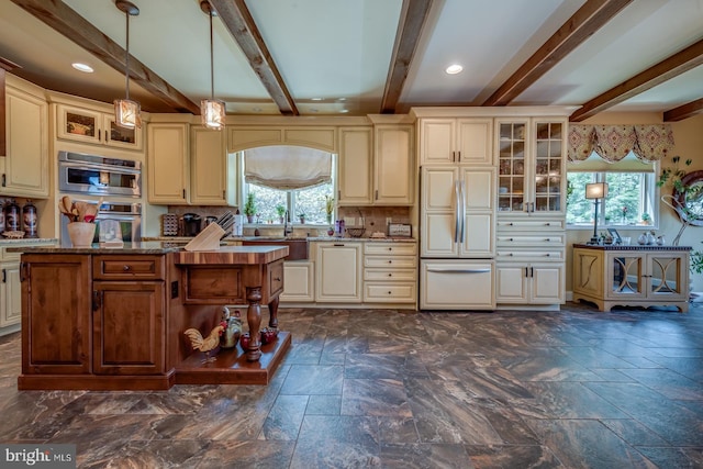 kitchen featuring paneled fridge, cream cabinets, plenty of natural light, beamed ceiling, and recessed lighting