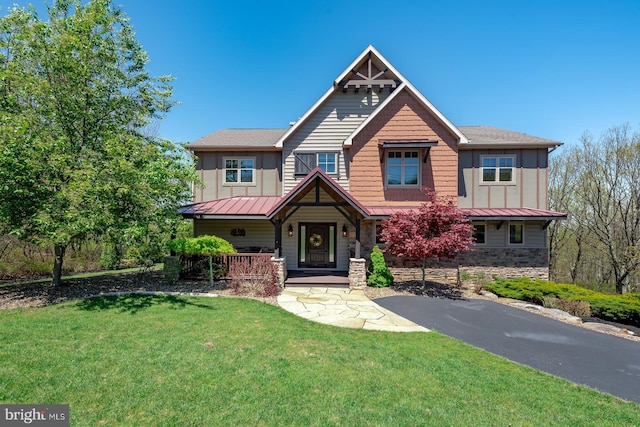 craftsman inspired home featuring a standing seam roof, a front yard, metal roof, covered porch, and stone siding