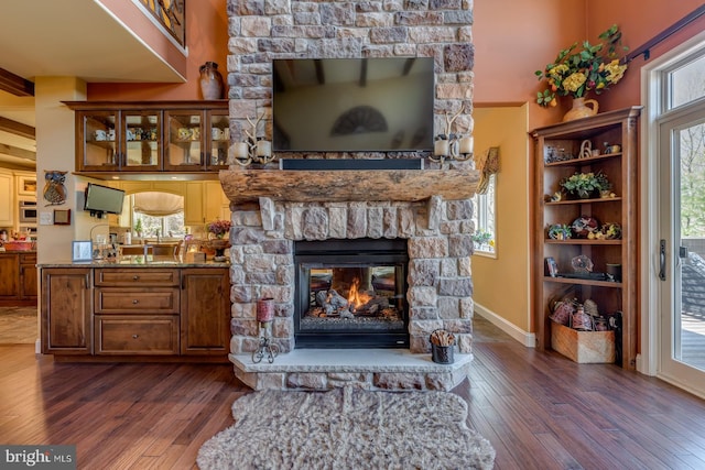 living area featuring dark wood-style flooring, a fireplace, and baseboards