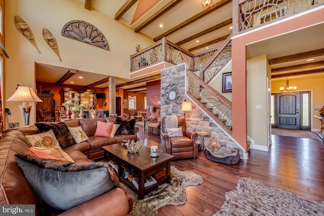 living area featuring beamed ceiling, a chandelier, stairs, wood finished floors, and a towering ceiling