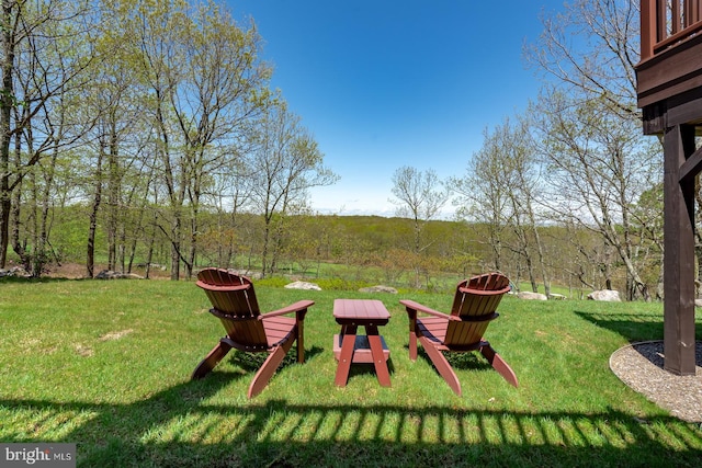 view of green lawn with a wooded view