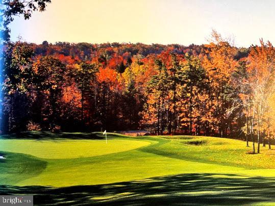 view of home's community featuring golf course view, a putting green, and a lawn