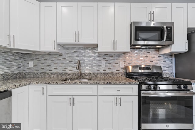 kitchen featuring stainless steel appliances, a sink, white cabinets, and backsplash