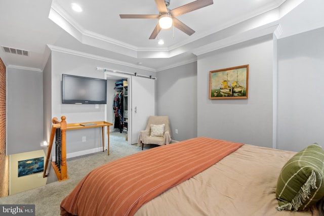 carpeted bedroom with a raised ceiling, crown molding, a spacious closet, a closet, and baseboards