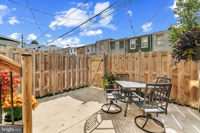 view of patio with fence, outdoor dining space, and a gate