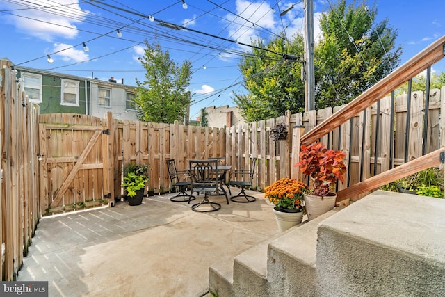 view of patio with a fenced backyard, outdoor dining area, and a gate
