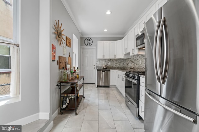 kitchen with stainless steel appliances, crown molding, white cabinetry, tasteful backsplash, and dark stone countertops