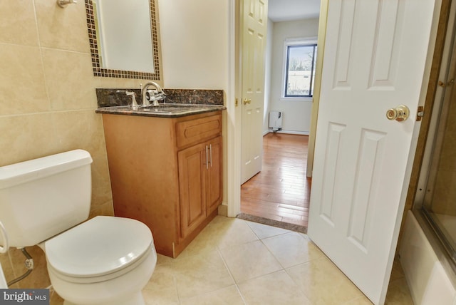 146 Monroe St Unit 101, Rockville, MD 20850 - bathroom with toilet, vanity, tile walls, tile patterned flooring, and radiator