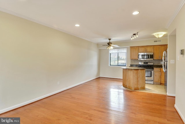 146 Monroe St Unit 101, Rockville, MD 20850 - kitchen with appliances with stainless steel finishes, crown molding, ceiling fan, a center island, and light wood finished floors