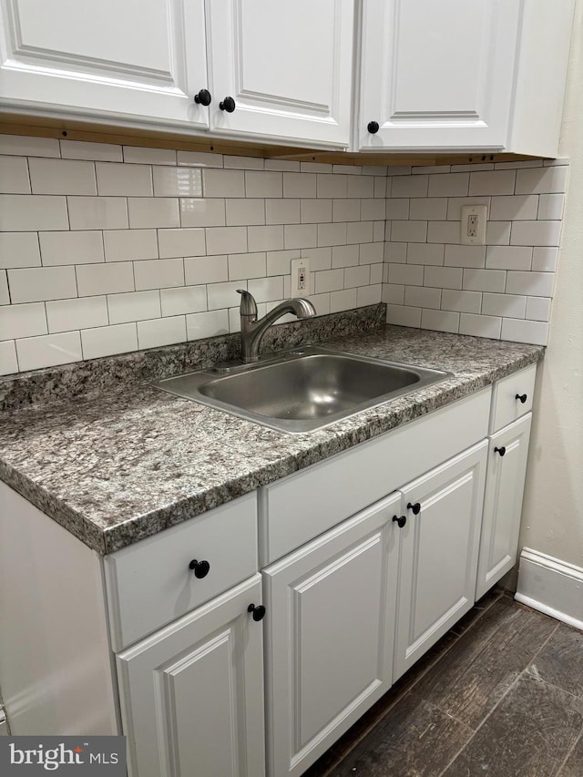 kitchen featuring a sink, white cabinetry, baseboards, and tasteful backsplash