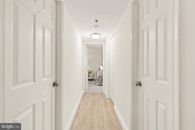 hall with light wood-type flooring and baseboards