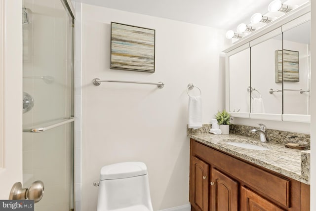 bathroom with a tile shower, toilet, and vanity