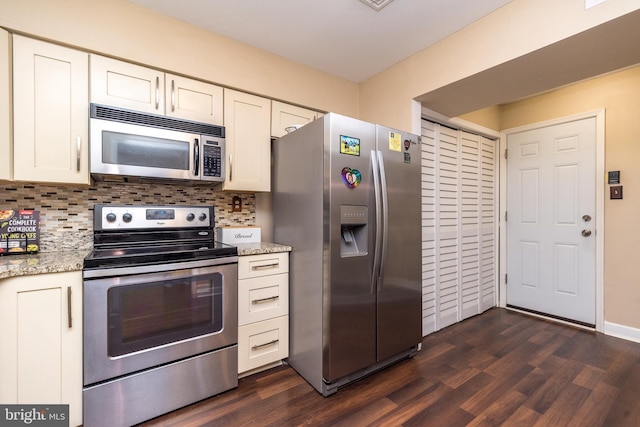 kitchen with appliances with stainless steel finishes, white cabinets, backsplash, dark wood-type flooring, and light stone counters