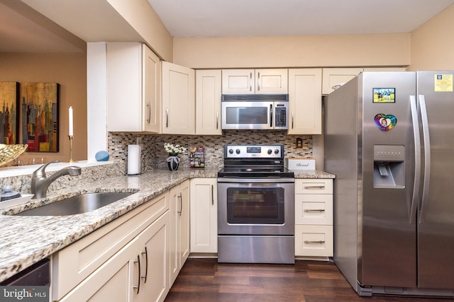 kitchen featuring stainless steel appliances, a sink, dark wood-style flooring, light stone counters, and white cabinetry