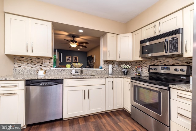 kitchen with stainless steel appliances, a sink, ceiling fan, decorative backsplash, and white cabinets