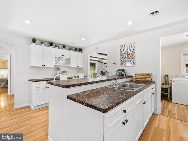 kitchen with a sink, washer / dryer, a peninsula, light wood-style floors, and recessed lighting