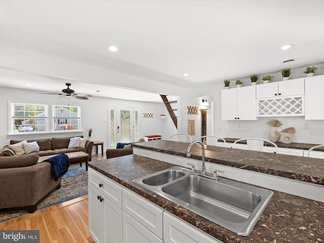 kitchen featuring a sink, open floor plan, white cabinets, and recessed lighting