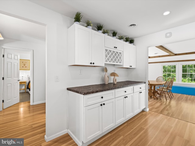 kitchen featuring light wood finished floors, white cabinets, dark stone countertops, and recessed lighting