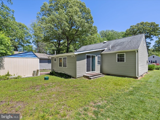 back of house with a yard and a shingled roof