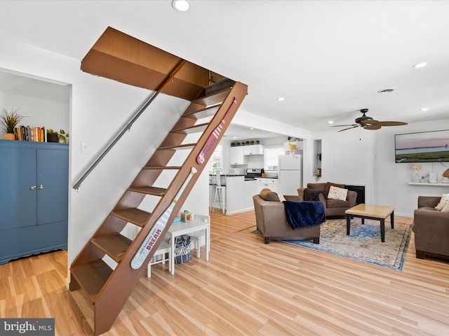living area featuring stairs, ceiling fan, light wood-style flooring, recessed lighting, and baseboards