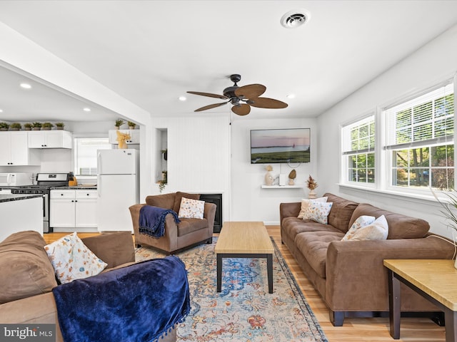 living room featuring light wood-style flooring, ceiling fan, and recessed lighting