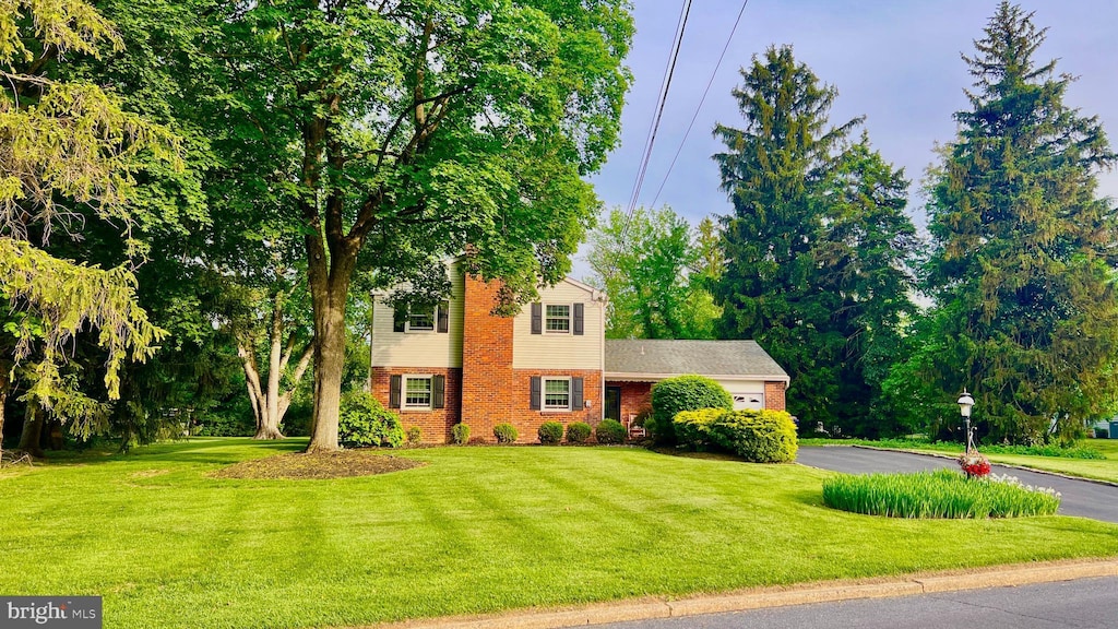 view of front of home featuring brick siding, a front yard, an attached garage, and driveway