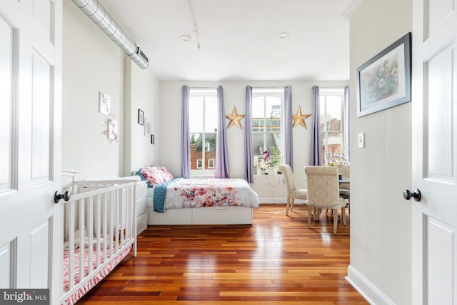 bedroom featuring wood-type flooring, track lighting, and baseboards