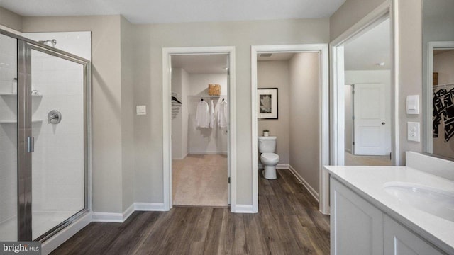 full bathroom featuring wood finished floors, a stall shower, toilet, and baseboards
