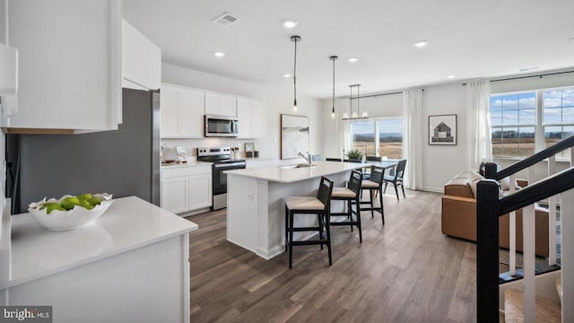 kitchen with stainless steel appliances, a sink, dark wood finished floors, light countertops, and recessed lighting