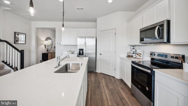 kitchen featuring stainless steel appliances, a sink, light countertops, dark wood-style floors, and white cabinetry