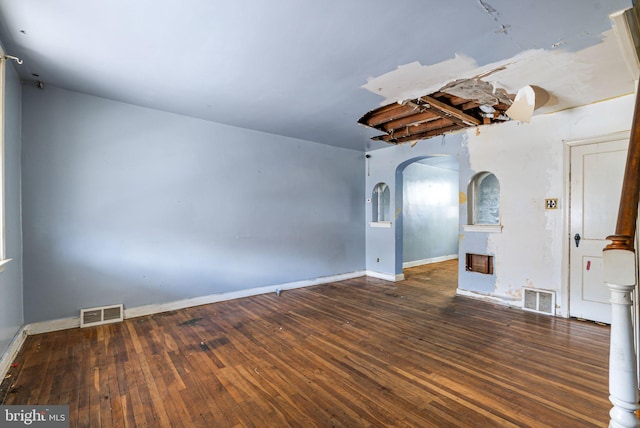 unfurnished room featuring arched walkways, hardwood / wood-style flooring, and baseboards