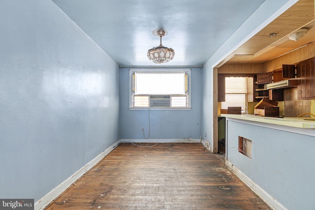 unfurnished dining area featuring hardwood / wood-style floors and baseboards