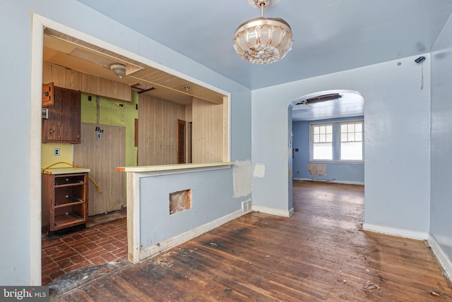 kitchen featuring arched walkways, a chandelier, and baseboards