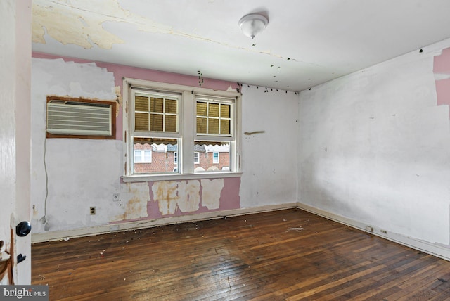 spare room featuring wood-type flooring and an AC wall unit
