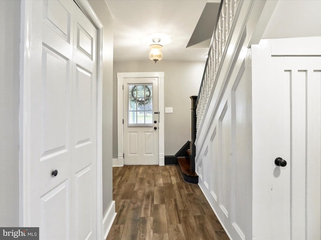 doorway with stairs, dark wood-type flooring, and baseboards