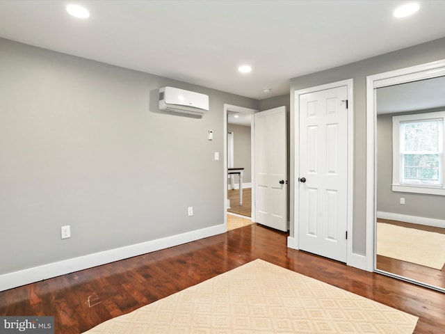 unfurnished bedroom with a wall mounted AC, baseboards, wood finished floors, and recessed lighting
