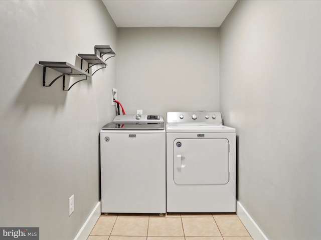 laundry area featuring washer and dryer, light tile patterned floors, and baseboards