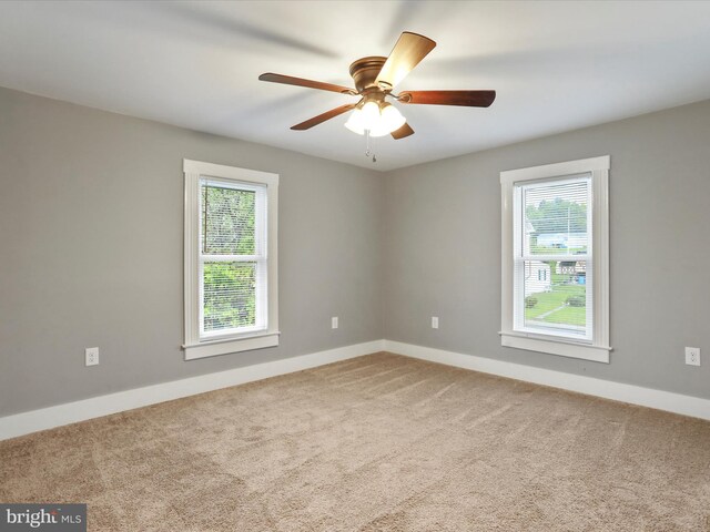 carpeted empty room with healthy amount of natural light, baseboards, and ceiling fan