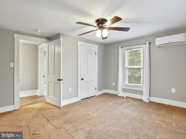 unfurnished bedroom with a wall mounted air conditioner, carpet, baseboards, and a ceiling fan