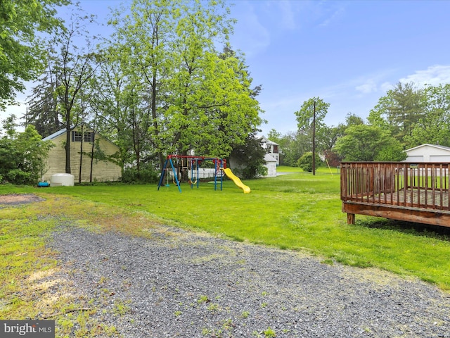 view of grassy yard featuring a playground and a wooden deck
