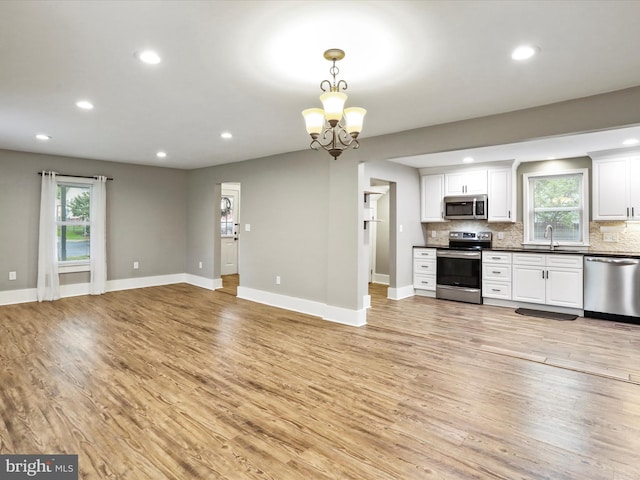 kitchen featuring appliances with stainless steel finishes, a sink, light wood-style floors, dark countertops, and open floor plan