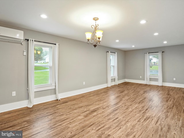 unfurnished room with a wall unit AC, wood finished floors, plenty of natural light, and recessed lighting