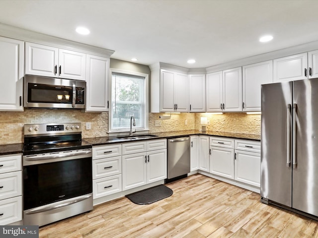 kitchen with stainless steel appliances, a sink, white cabinetry, light wood-style floors, and recessed lighting