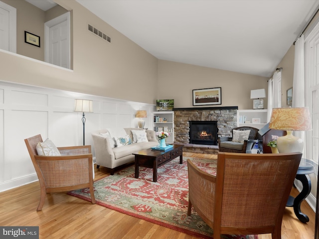 101 Gothard Rd, Lutherville Timonium, MD 21093 - living room featuring a decorative wall, wood finished floors, a stone fireplace, lofted ceiling, and a wainscoted wall