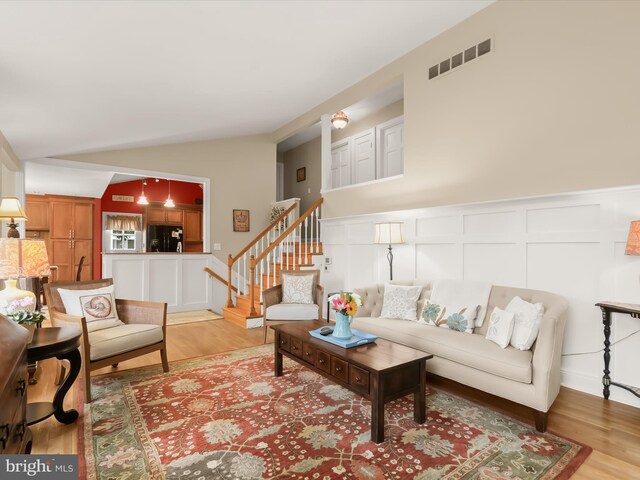 101 Gothard Rd, Lutherville Timonium, MD 21093 - living area with a decorative wall, lofted ceiling, light wood-style flooring, stairway, and a wainscoted wall