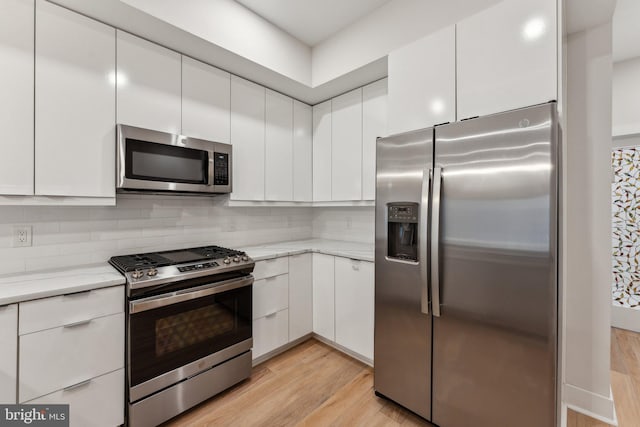 1645 W Virginia NE Unit 1, Washington, DC 20002 - kitchen featuring stainless steel appliances, light wood-type flooring, white cabinets, backsplash, and light stone countertops
