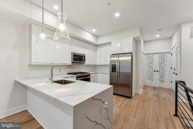 1645 W Virginia NE Unit 1, Washington, DC 20002 - kitchen with appliances with stainless steel finishes, a peninsula, light wood-style flooring, decorative backsplash, and white cabinets