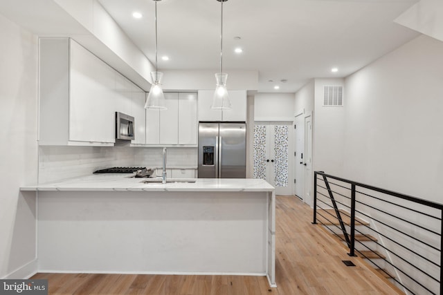 1645 W Virginia NE Unit 1, Washington, DC 20002 - kitchen with stainless steel appliances, a sink, a peninsula, white cabinetry, and backsplash