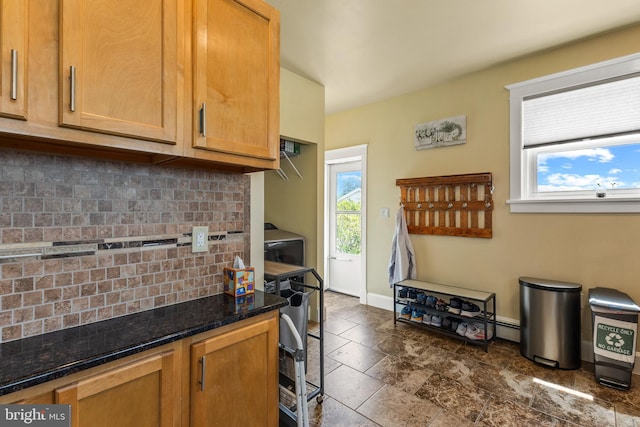 kitchen featuring backsplash, baseboards, dark stone counters, and dark stone finish floors