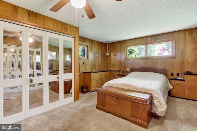 bedroom with light colored carpet, wood walls, and a ceiling fan